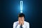 Worried young businessman covering face with hands. Glowing exclamation mark hologram above head on blue background. Stress,