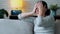 Worried young woman thinking while sitting on sofa in the living room at home.