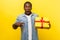 Wow, amazing present! Portrait of shocked man pointing at gift box. isolated on yellow background