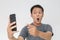 Wow face of Your Asian man shocked what he see in the smartphone on  grey background