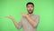 Wow, look here! Extremely happy amazed man in shirt holding palm and pointing copy space. studio shot