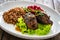 Wrapped beef in sauce served with boiled buckwheat and grated beets on wooden table