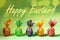 Wrapped in festive colored paper Easter eggs are standing in row on neo mint green with bokeh with words Happy Easter.