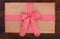 Wrapped gift box with red and white checkered ribbon bow on a dark walnut wood, top view, close up