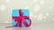 Wrapped gift. close-up. blue gift box with pink ribbon. white bokeh background with a slight shimmer.