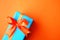 Wrapped present box on orange bright background. Holiday concept.
