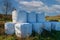 Wrapped straw bales. The bales are stacked in a meadow and covered with a tarpaulin against the rain