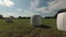 Wrapped white hay rolls on meadow, time lapse