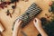 Wrapping rustic christmas present. Hands wrapping christmas gift in stylish striped paper and pine branches, cones, gingerbread