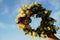 Wreath of different flowers on a background of blue sky. flowers wreath in women hands in the evening sunset