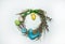 A wreath of dried herbs, willow branches with fluffy buds, colorful eggs and cute handmade textile toys on a white background.