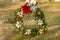 Wreath with flowers and cones against sunlit lawn