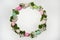 A wreath of green leaves, pink-and-white apple blossoms and colorful eggs on a white background.
