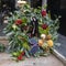 wreath made of fir, decorated with dry tangerines, lotus, herbs, berries in green and orange tones for sale at the