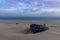 Wreck of an old wooden rowboat buried in the sand with a beautiful sunset sky and ocean behind