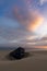 Wreck of an old wooden rowboat buried in the sand with a beautiful sunset sky and ocean behind