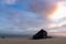 Wreck of an old wooden rowboat buried in the sand with a beautiful sunset sky and ocean behind