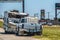 Wrecked camper trailer with part of back ripped off beside road with pickup parked in front of it - background of signs and