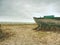 Wrecked fishing boat on old dry grass. Abandoned wooden ship with damaged engine