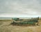 Wrecked fishing boat on old dry grass. Abandoned wooden ship with damaged engine