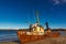 A wrecked ship on a sandy beach at low tide in the Teriberskaya Bay. Far North, Barents Sea in Russia