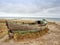 Wrecked wooden fisher boat. Broken abandoned boat in sand of sea bay.