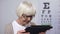 Wrinkled elderly woman holding tab and trying to read, unhappy with poor sight