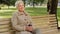 Wrinkled face of 60s happy elderly woman outdoors in park looking aside having wide smile, dental implants and