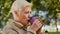 Wrinkled face of 60s happy elderly woman outdoors in park looking aside having wide smile, dental implants and