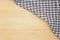 Wrinkled grey gingham fabric on rustic light brown wood background.