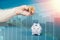 Wrinkled hand of an elderly woman show a bitcoin near a piggy bank. Business chart on the background. Double exposure