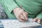 Wrinkled hand of old person solving crossword puzzle