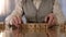 Wrinkled pensioner making word lonely of wooden cubes on table, nursing home