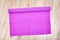 Wrinkled purple paper lies on an oak board.