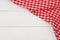 Wrinkled red gingham fabric on rustic white wood plank background.