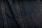 Wrinkled worn denim or grunge jeans fabric texture with orange tint and seams. Close up background or backdrop. Textile