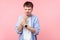 Wrist pain. Portrait of upset brown-haired man clutching his injured wrist grimacing from pain. indoor studio shot pink background