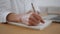 Writer hands noting information at home close up. Woman writing notepad at desk