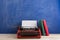 writer's workplace - red typewriter and books on blue blackboard background