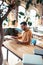 Writer wearing orange polo neck sitting at the wooden table