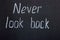 Writing on the black board `never look back`