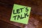 Writing on colorful sticky note Let`s talk. Text with Let`s talk on paper