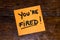 Writing on colorful sticky note you are fired. Text with you are fired on paper