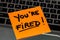 Writing on colorful sticky note You are fired. Text with You are fired on paper. Sticky note, post it on keyboard
