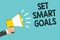 Writing note showing Set Smart Goals. Business photo showcasing Establish achievable objectives Make good business plans Man holdi