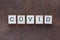 written `COVID` with light wood letters