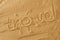 Written hashtag travel with sun sign and beam on sand of beach wave background