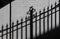 Wrought iron fence casts its stark shadow reflected on the adjacent white brick wall