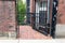 Wrought iron gate door over brick sidewalk passage between buildings