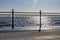 Wrought iron railing at the pier and shadows with sunlight and waves